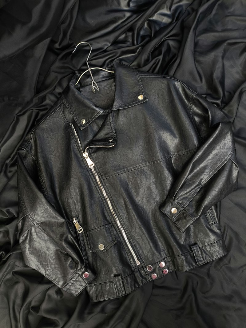 Jaket kulit hitam terlipat di atas kasur